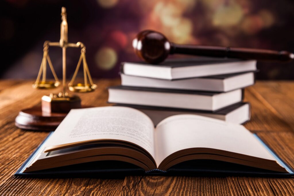 An open book, a judge's gavel and a justice scale, representing how one can benefit from calling a Portland criminal defense lawyer.