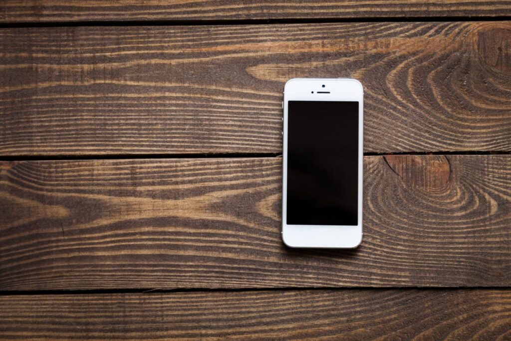 A white cellphone on a wooden table, representing how one can benefit from calling a Portland criminal defense lawyer.