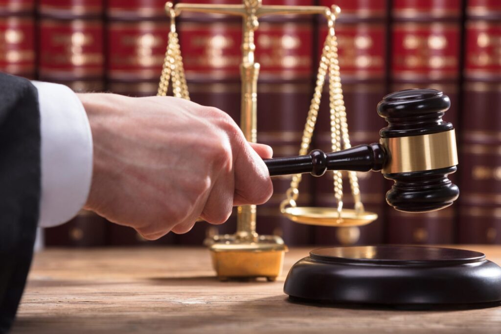 A judge hitting a block with a gavel and a liberty scale in the background, representing how one can benefit from calling a Portland criminal defense lawyer.