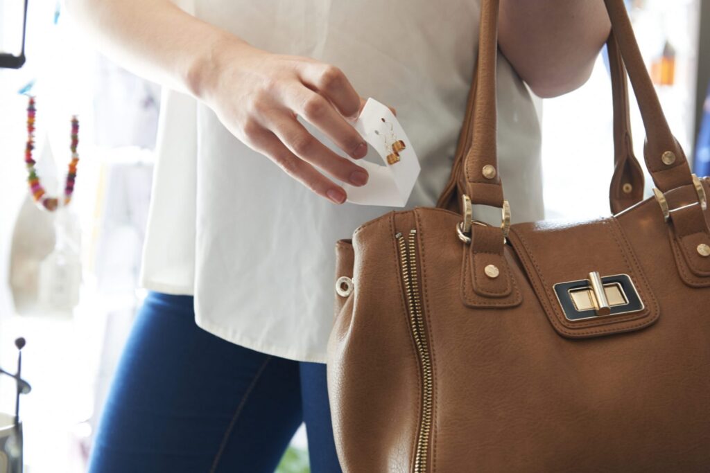 A woman putting a pair of earrings in her purse, making it seem like she stole them representing how one can benefit from calling a Maine criminal defense lawyer.