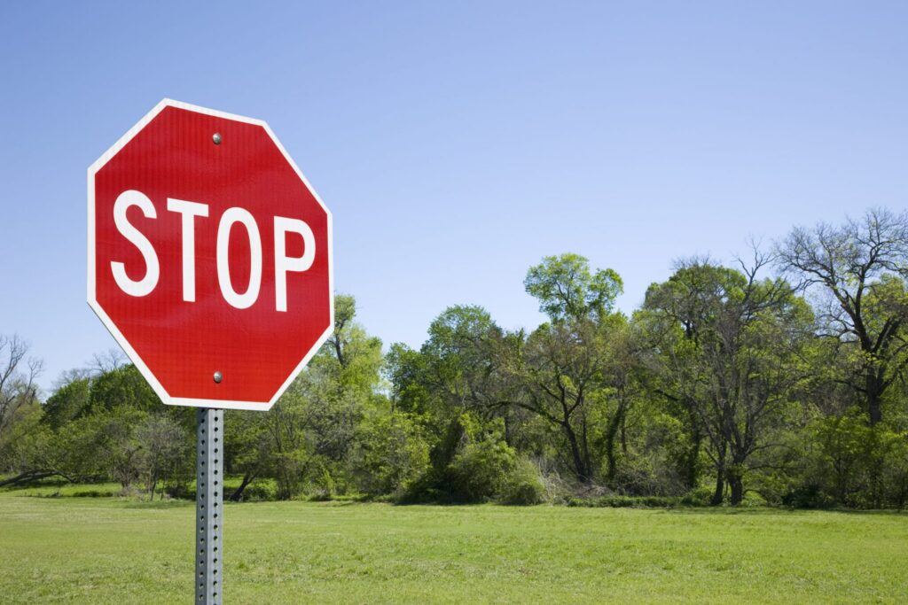 A traffic stop sign with a field in the background, representing how one can benefit from calling a Maine criminal defense lawyer.