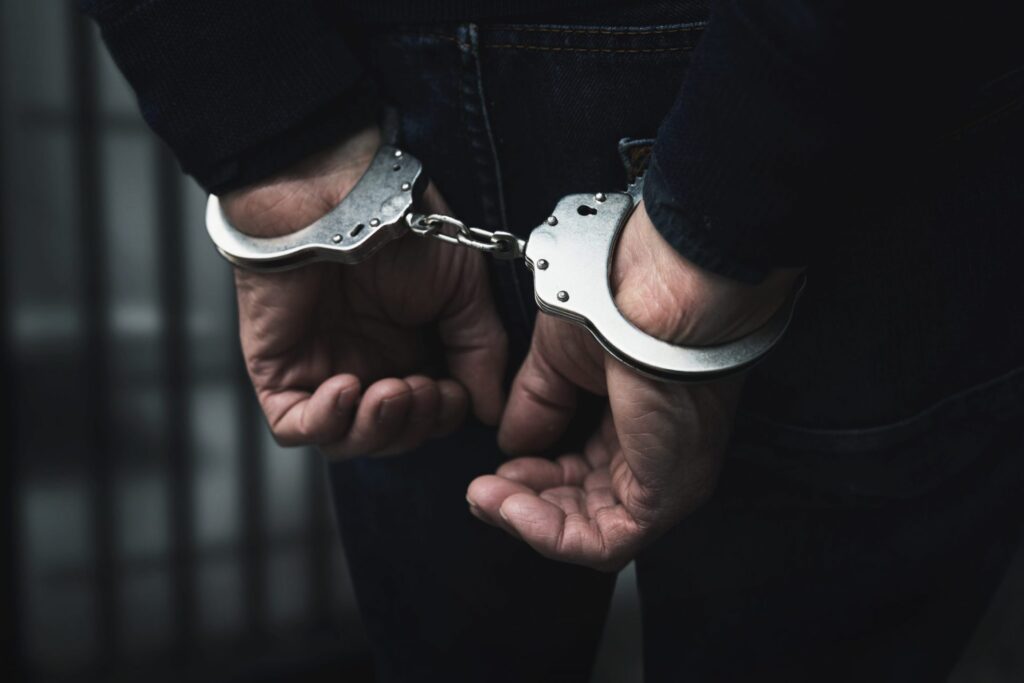 A man with handcuffs, representing how one can benefit from calling a Maine criminal defense lawyer.