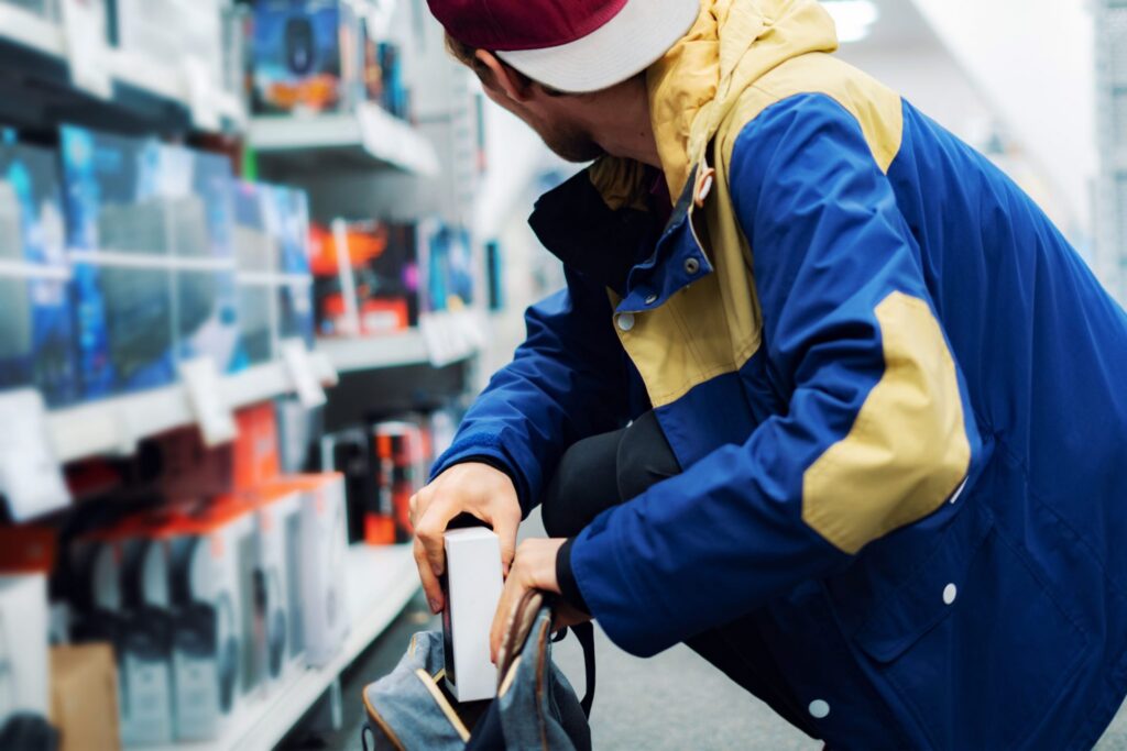 A man at a store putting a book he did not pay for in his bag, representing how one can benefit from calling a Criminal Law Attorney in Auburn.