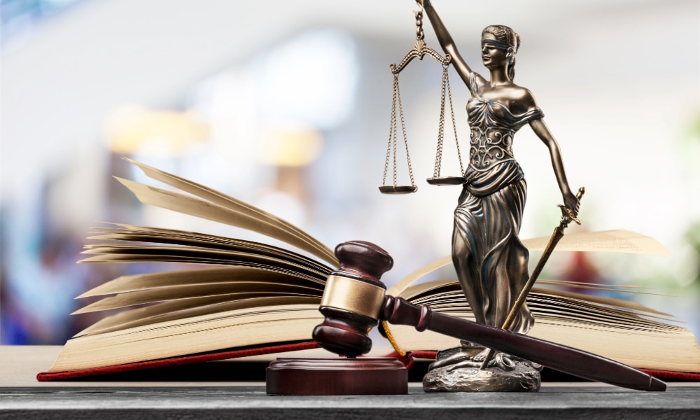 Auburn Maine Sexual Assault Defense Lawyers portrayed by lady justice next to a gavel and a legal text on a desk.
